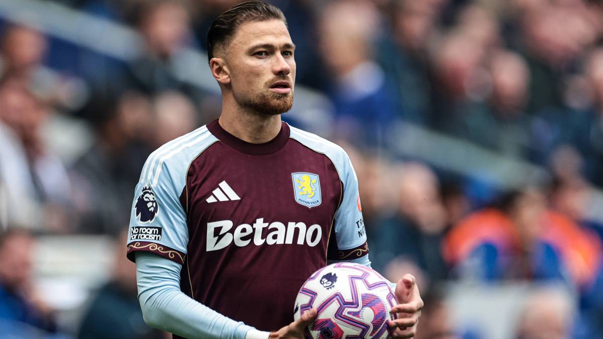 Piłkarz w koszulce Aston Villi z herbem klubu i napisem "Betano" na piersi, trzymający piłkę.