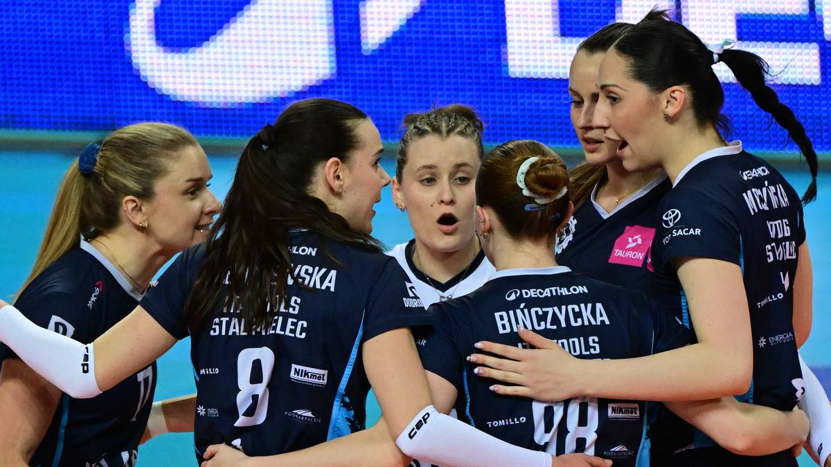 Siatkarki w ciemnogranatowych strojach stoją w grupie, przytulając się do siebie, z widocznymi numerami na koszulkach i nazwiskiem "BUNCZYCKA".