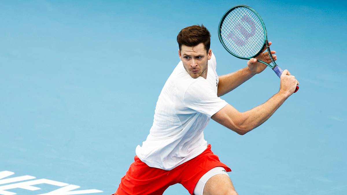 Tenisista wykonujący forhend na niebieskim korcie z napisem SYDNEY