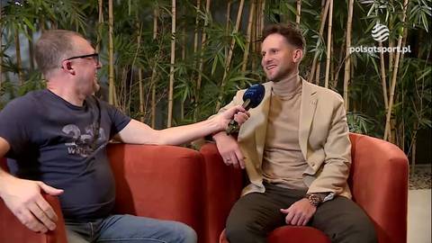 Maciej Ryszczuk siedzi na kanapie i udziela wywiadu, trzymając mikrofon. Obok niego siedzi dziennikarz.