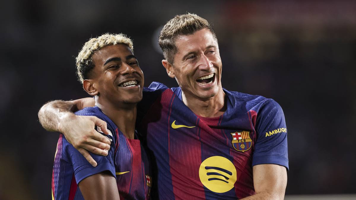 Dwóch piłkarzy w niebiesko-bordowych strojach piłkarskich, jeden z nich obejmuje drugiego, obaj się uśmiechają.