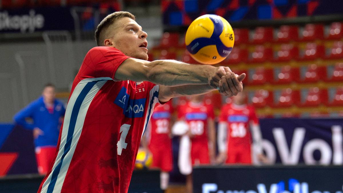 Siatkarz w czerwonej koszulce z numerem 4 zagrywa piłkę.