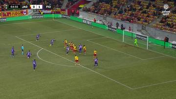 Boisko piłkarskie z zawodnikami Jagiellonii Białystok i Fiorentiny. Na tablicy wyników widnieje wynik 0:1 dla Fiorentiny. Gra toczy się w okolicach pola karnego.