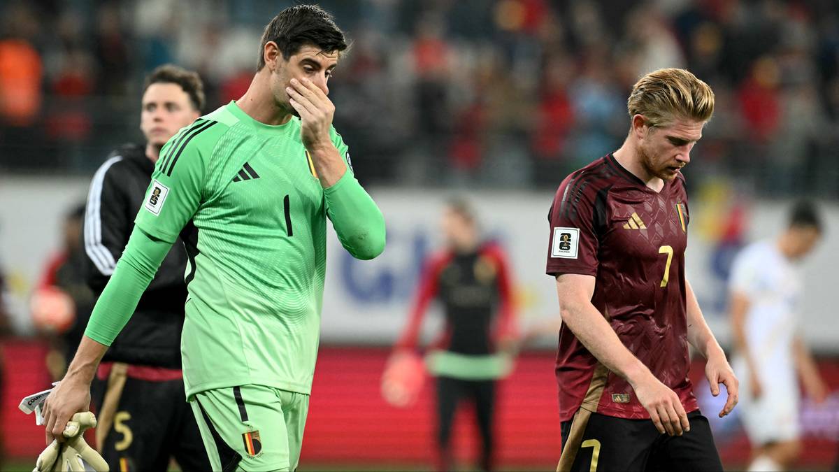 Piłkarz i bramkarz Belgii stoją smutni na boisku po przegranym meczu.