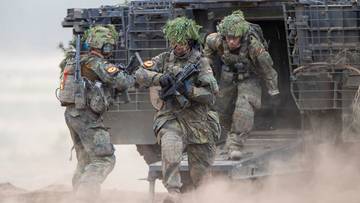 Trzech żołnierzy w umundurowaniu wychodzi z pojazdu wojskowego.