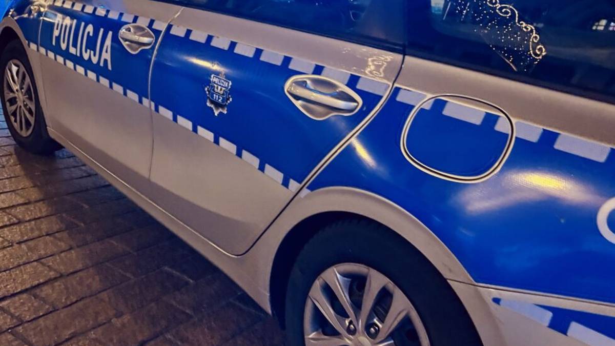 Widok z boku na policyjny radiow&oacute;z z widocznym napisem "POLICJA" na drzwiach.