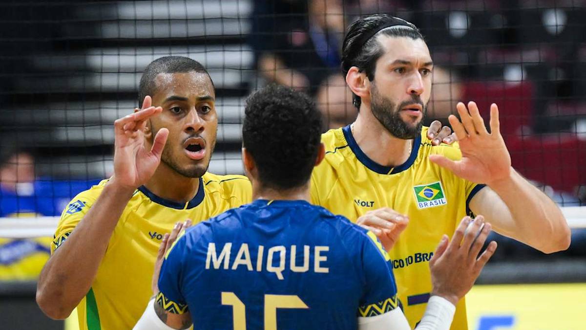 Trzech siatkarzy w żółtych koszulkach reprezentacji Brazylii na boisku.