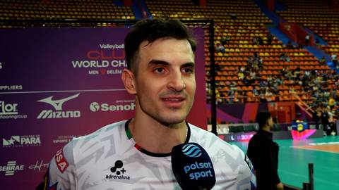 Portret Wassima Ben Tary, siatkarza, na tle hali sportowej z tablicami informacyjnymi i widownią.