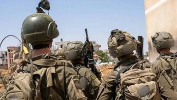 Żołnierze Izraelscy w hełmach i kamizelkach taktycznych patrzą w stronę zniszczonego krajobrazu.