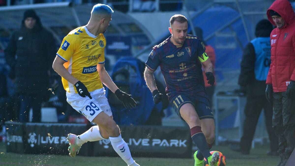 Dw&oacute;ch piłkarzy w akcji na boisku, jeden w ż&oacute;łtej koszulce z numerem 39, drugi w granatowej koszulce z numerem 11, obaj walczą o piłkę.