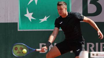 Tenisista wykonujący forhend na korcie ziemnym.