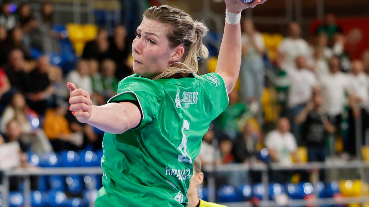 Piłkarka ręczna w zielonej koszulce rzuca piłkę do bramki, widoczna dynamika ruchu.