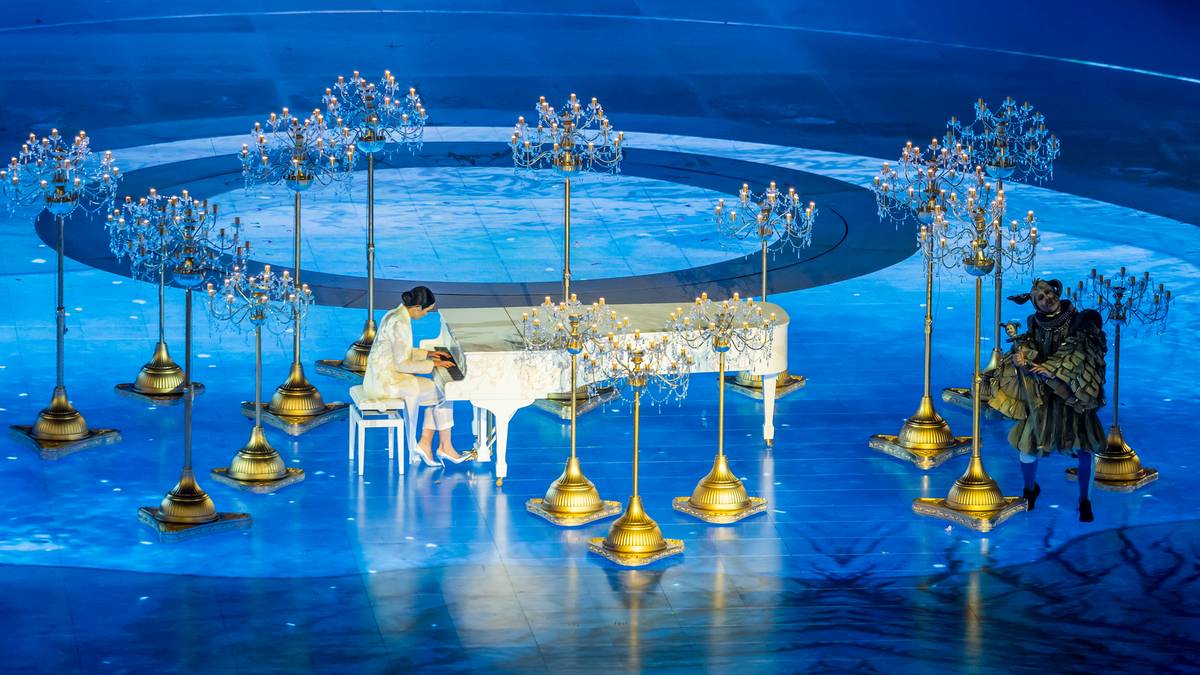 Osoba grająca na pianinie otoczona dekoracjami świetlnymi podczas ceremonii.