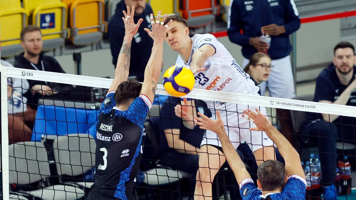 Siatkarz w białej koszulce z numerem 23 atakuje piłkę, blokowany przez zawodnika w czarnej koszulce z numerem 3.