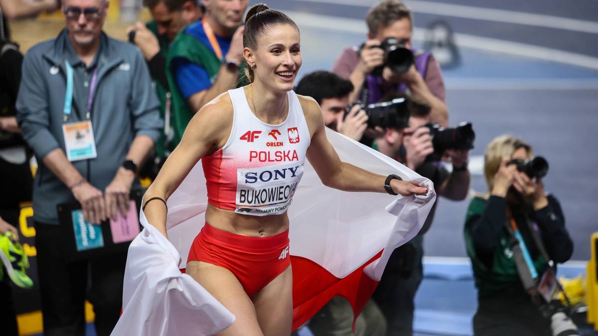 Uśmiechnięta lekkoatletka w biało-czerwonym stroju z polską flagą na ramionach.