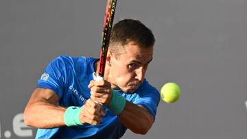 Tenisista Daniel Michalski w akcji, uderzający piłkę rakietą.