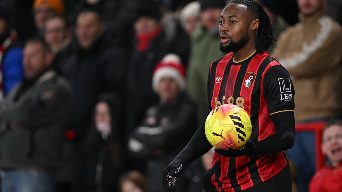 Piłkarz w czerwono-czarnej koszulce z numerem 24 trzyma piłkę.