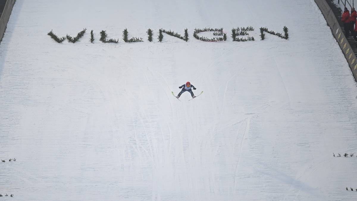 Widok z g&oacute;ry na skocznię narciarską w Willingen, z wyrytą nazwą miejscowości na zeskoku i pojedynczym skoczkiem na środku