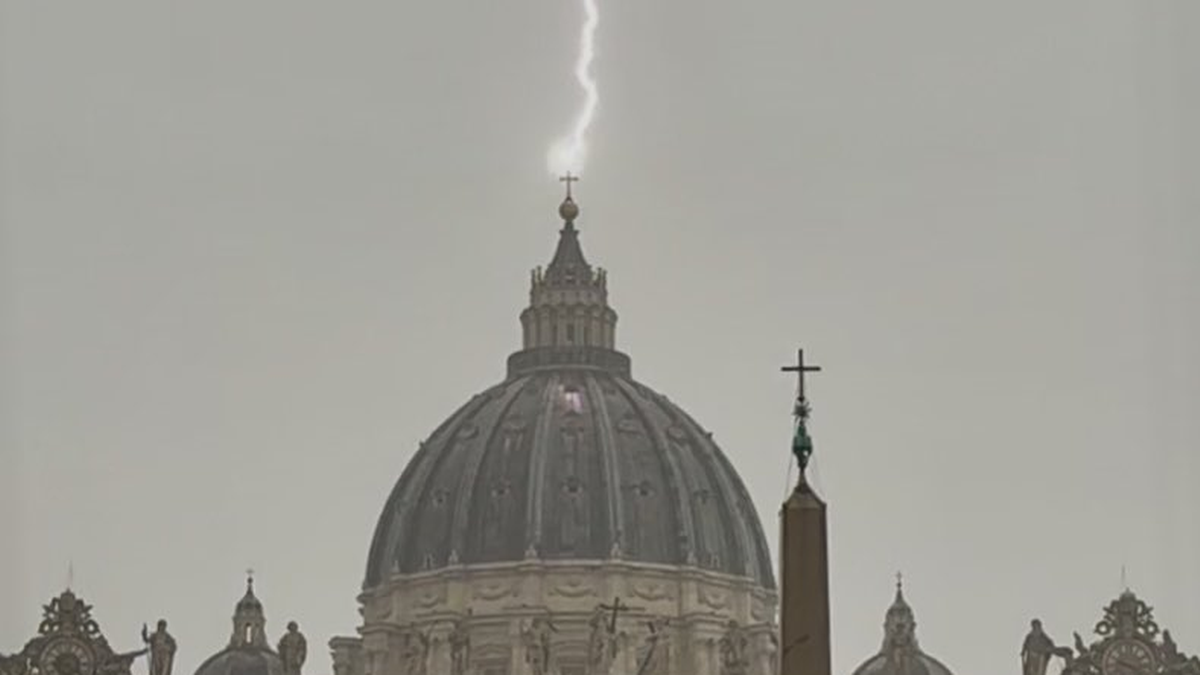 Uderzenie pioruna w szczyt kopuły bazyliki na tle burzowego nieba.