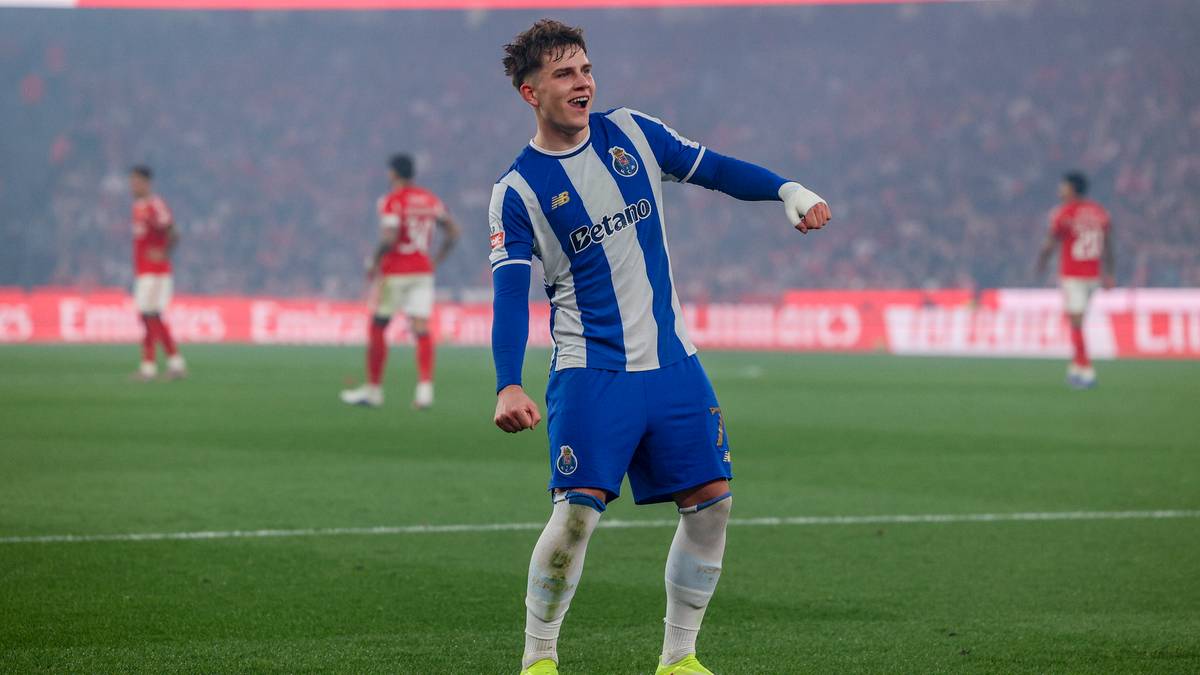 Piłkarz w niebiesko-białym stroju FC Porto świętuje na zielonym boisku, z innymi zawodnikami w tle.