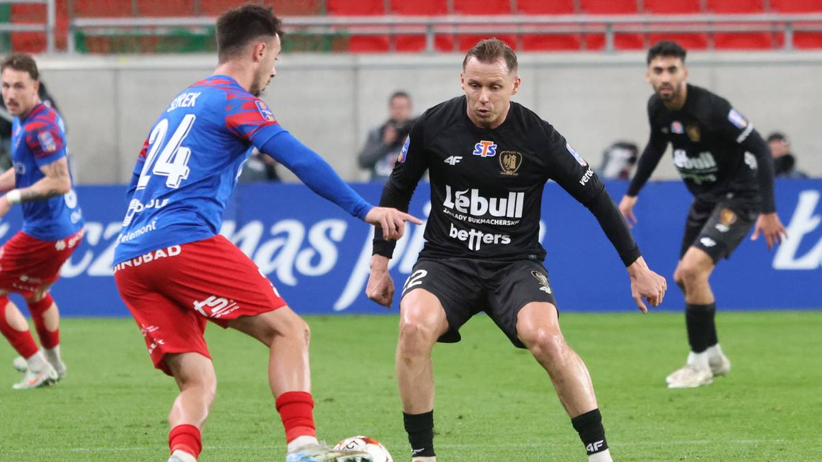 Dwóch piłkarzy walczy o piłkę na boisku podczas meczu piłki nożnej.