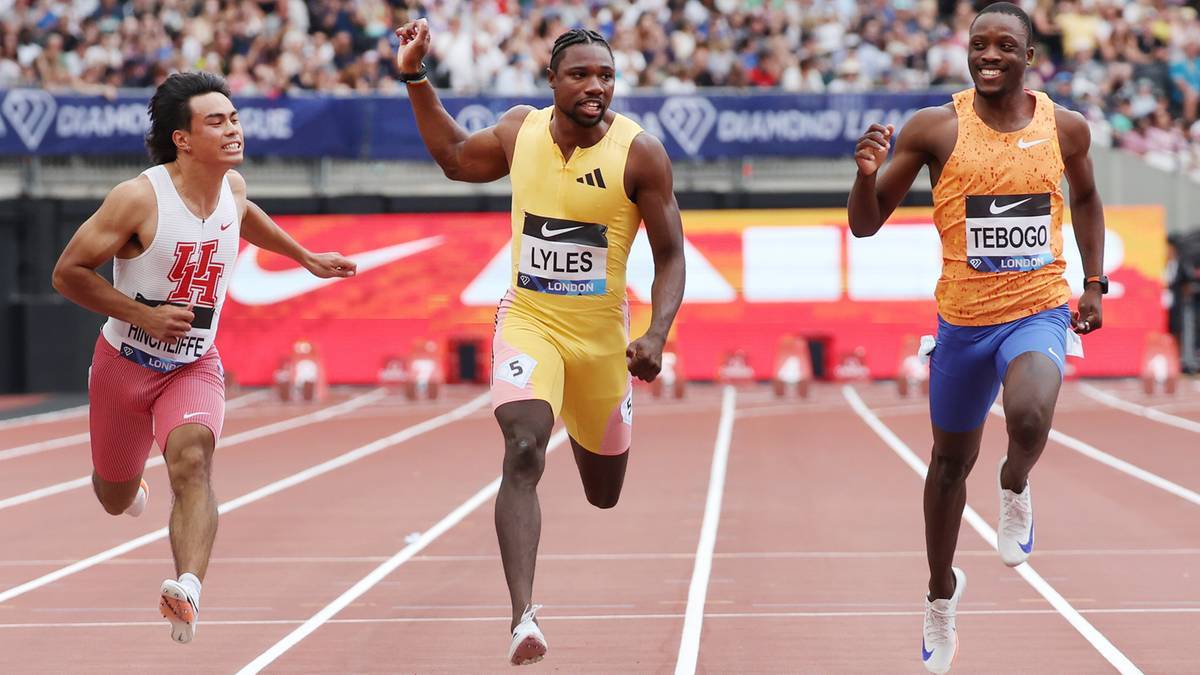 Trzech lekkoatletów biegnie po bieżni podczas zawodów. Na pierwszym planie jest zawodnik w żółtym stroju z numerem 123 i nazwiskiem "LYLES". Obok niego, po lewej, biegnie zawodnik w białej koszulce z numerem "14". Po prawej stronie widać zawodnika w pomarańczowej koszulce z nazwiskiem "TEBOGO". Wszyscy zawodnicy są w ruchu, na trzecim planie widownia.