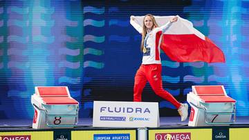 Pływaczka z flagą Polski na podium.