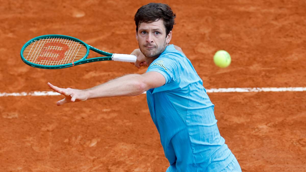 Tenisista wykonujący forhendowy uderzenie na ceglanym korcie.