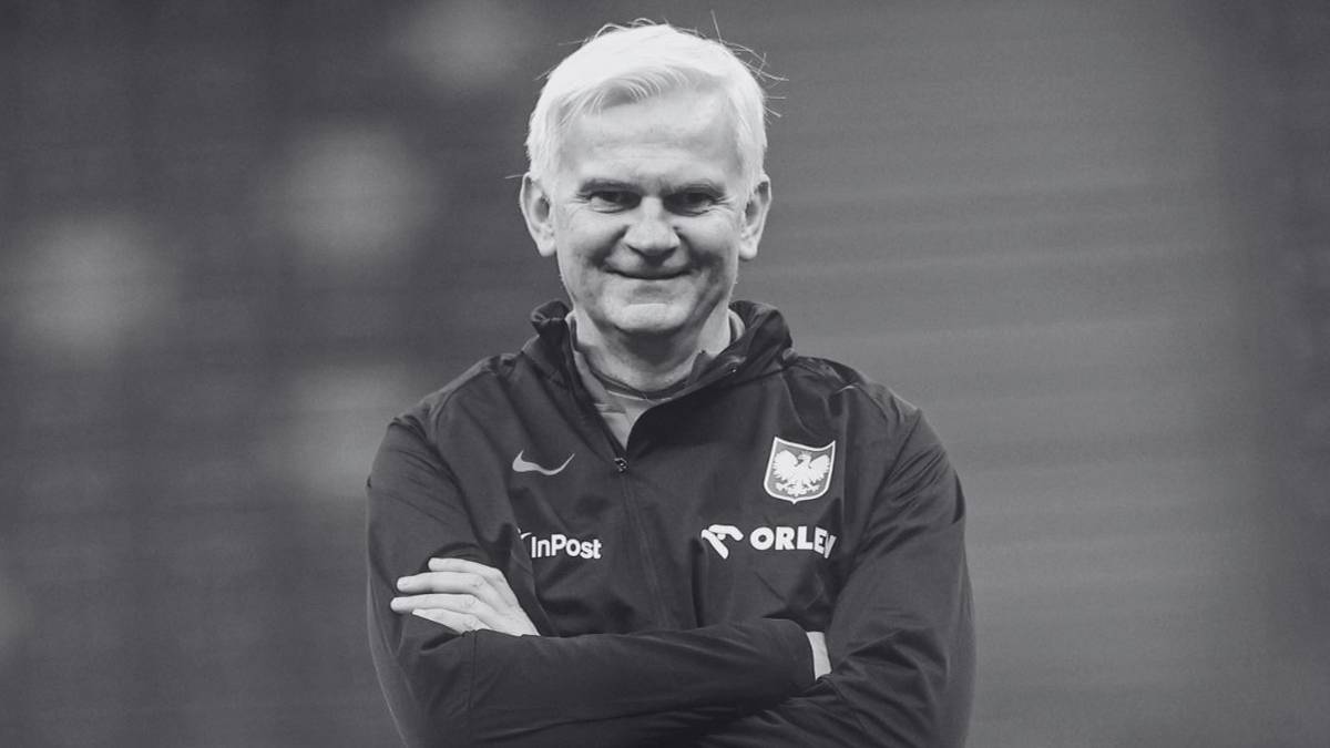 Jacek Magiera, drugi trener reprezentacji Polski, uśmiecha się do obiektywu ze skrzyżowanymi rękami.