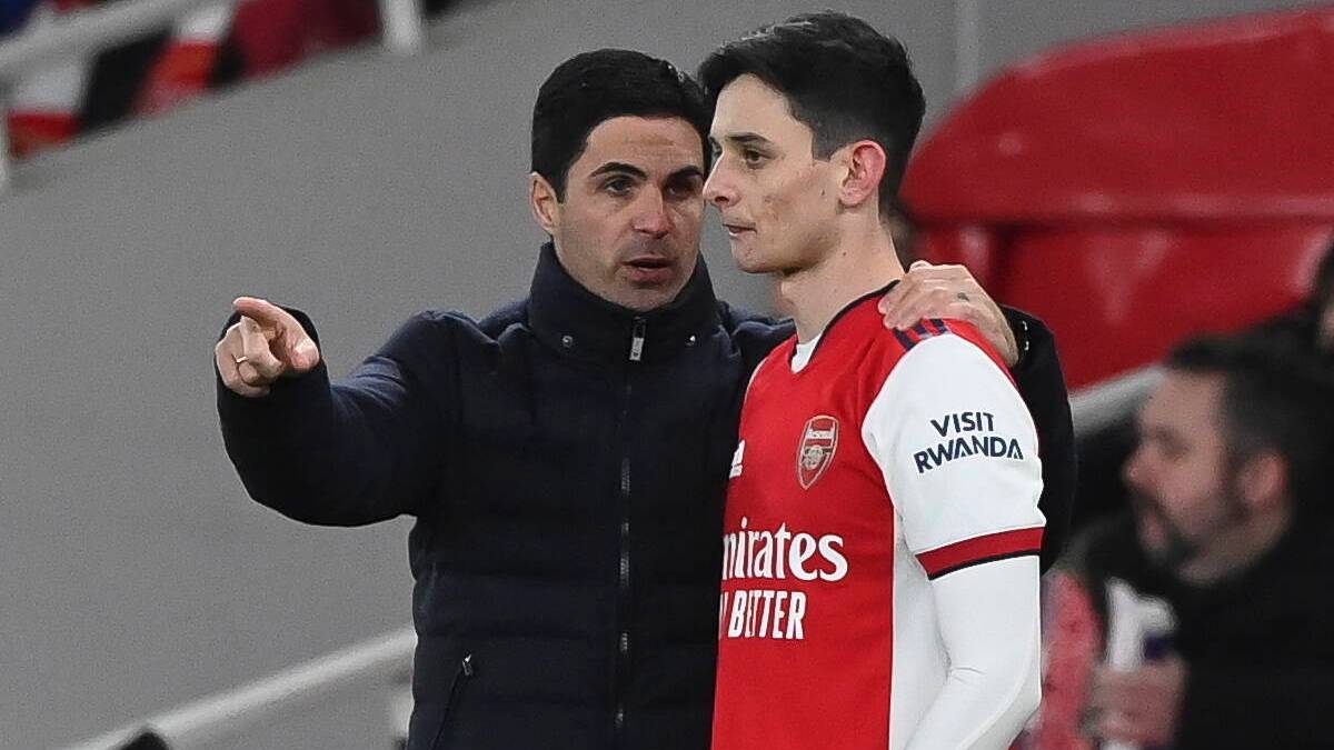 Trener piłkarski Mikel Arteta wskazuje coś na boisku młodemu zawodnikowi w koszulce Arsenalu z numerem 87.