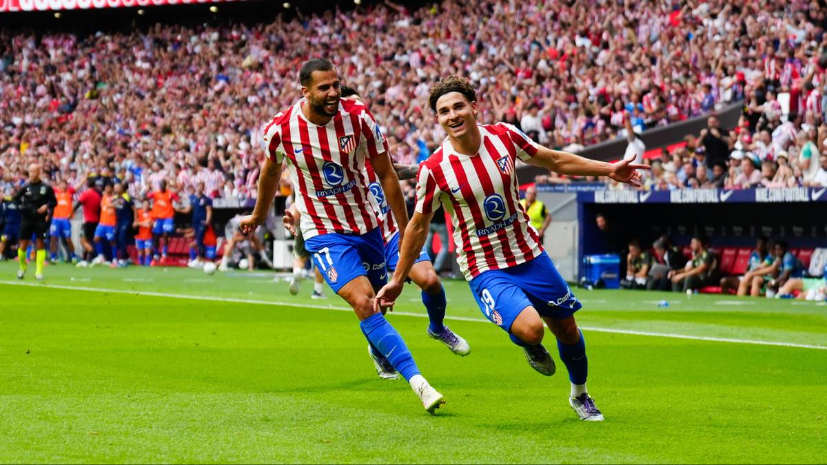 Dwóch piłkarzy Atletico Madryt w strojach w biało-czerwone pasy świętuje bramkę na tle trybun wypełnionych kibicami.