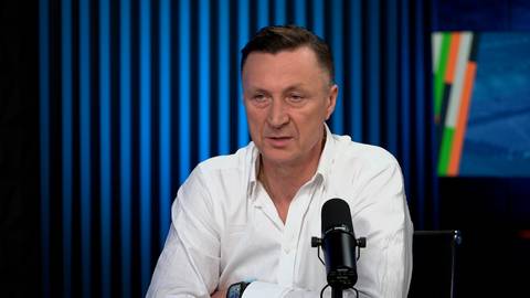 Tomasz Hajto siedzi przed mikrofonem w studiu telewizyjnym.