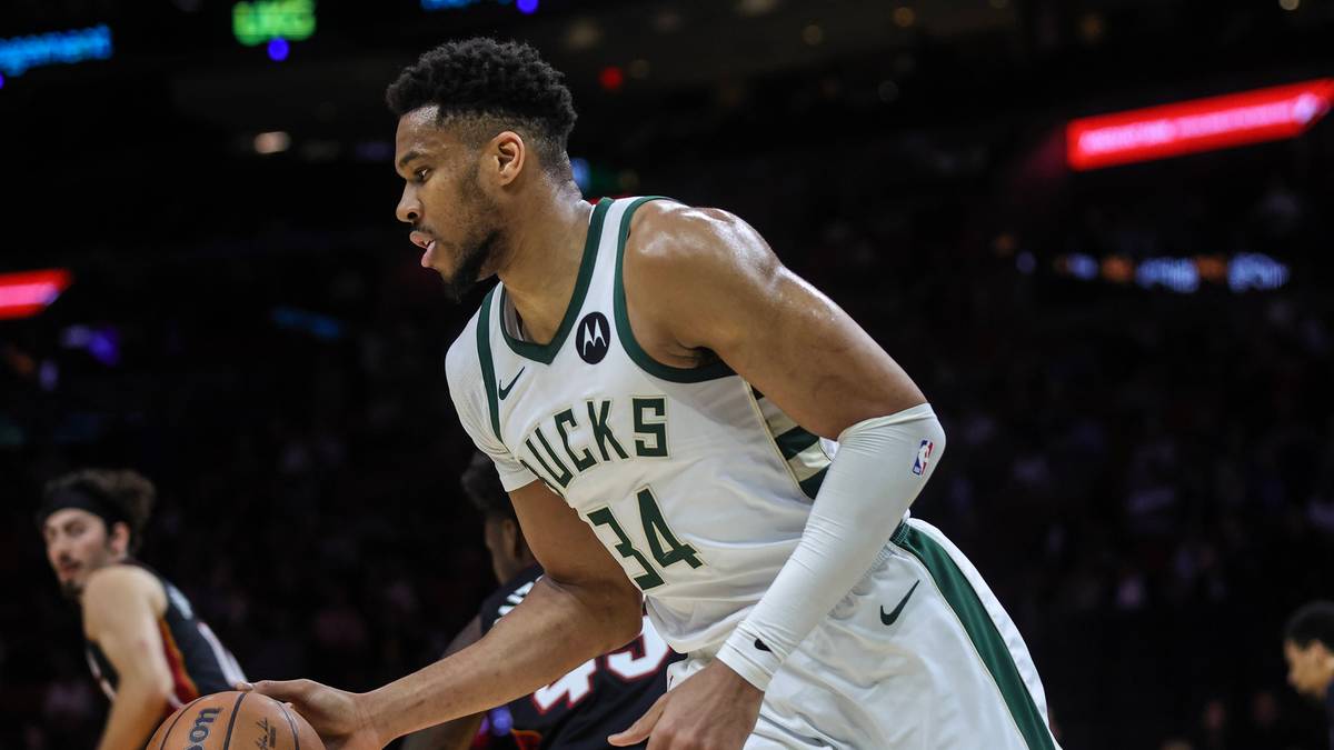 Giannis Antetokounmpo prowadzi piłkę do koszyk&oacute;wki podczas meczu, w białym stroju Milwaukee Bucks z numerem 34.