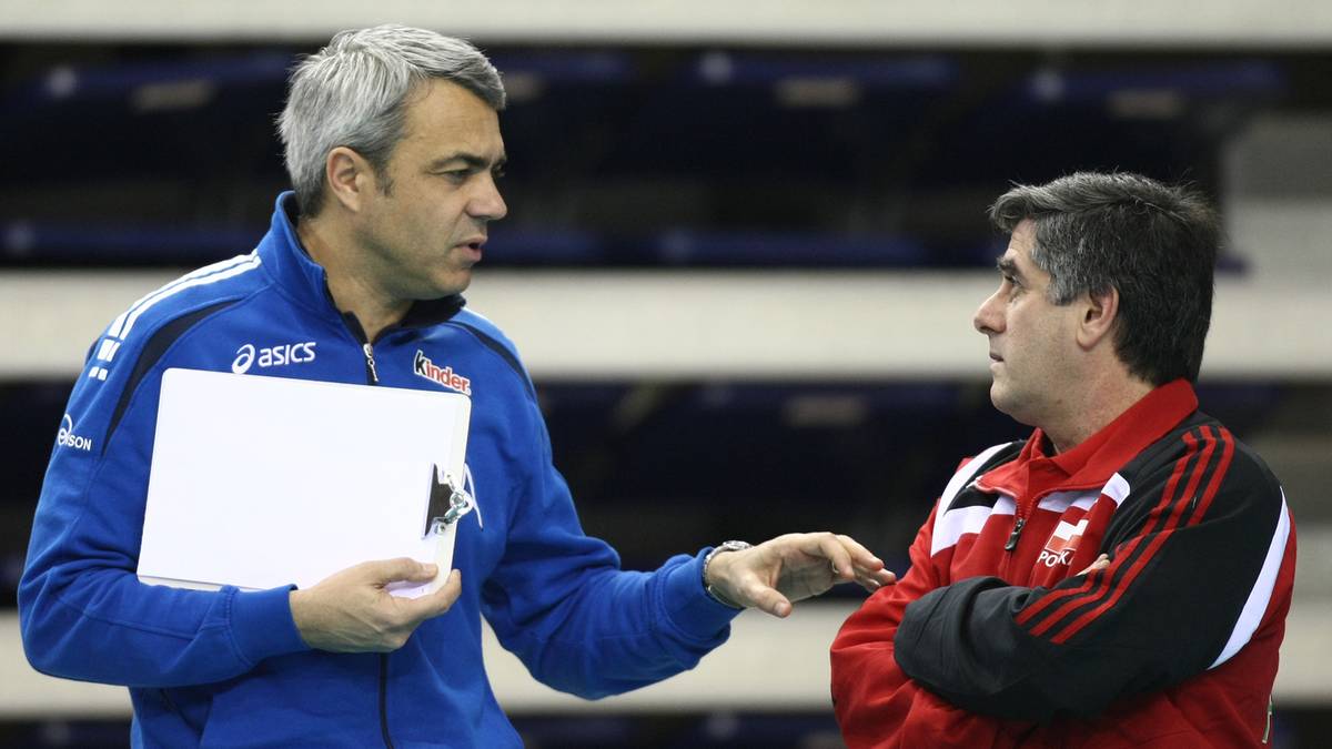 Dwóch mężczyzn w strojach sportowych rozmawia, jeden z nich trzyma białą kartkę.