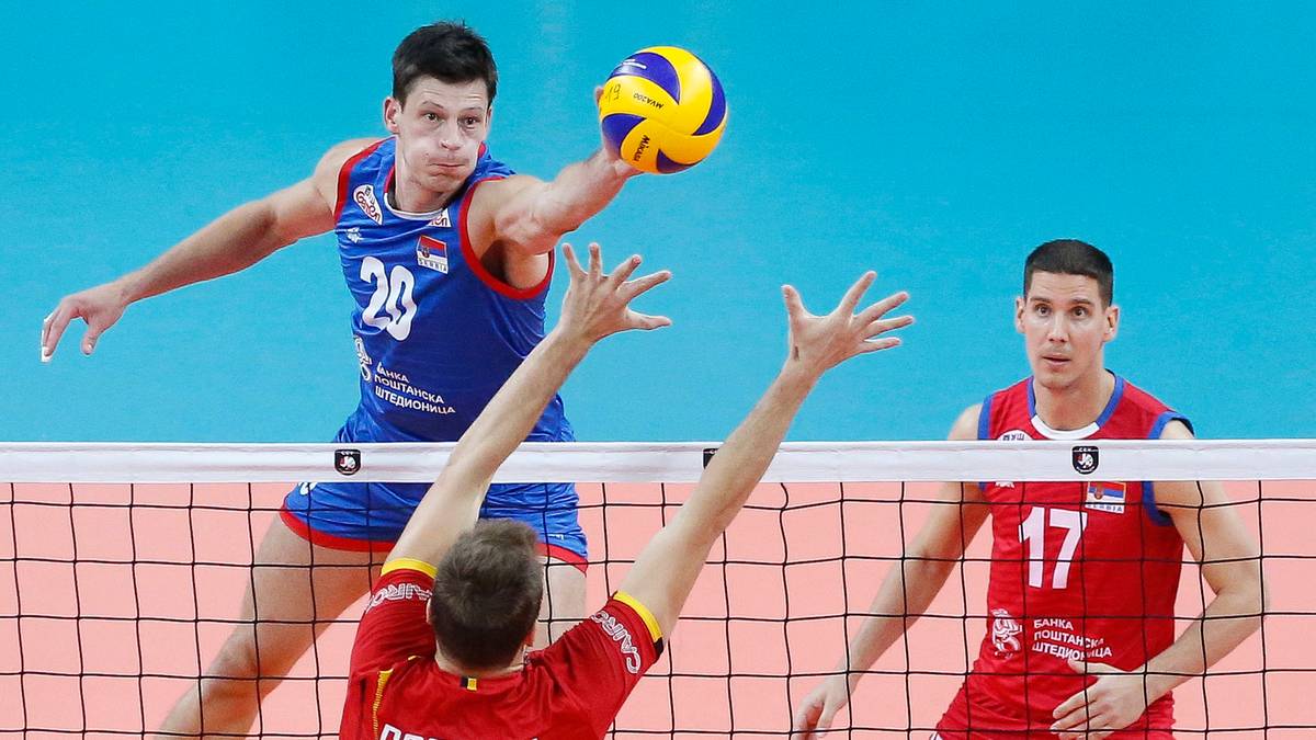 Siatkarz w niebieskiej koszulce z numerem 29 wykonuje zagrywkę piłki do siatkówki, podczas gdy inny zawodnik w czerwonej koszulce z numerem 17 przygotowuje się do bloku.