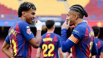 Dw&oacute;ch piłkarzy FC Barcelony w strojach klubowych, stojących obok siebie i rozmawiających na boisku.