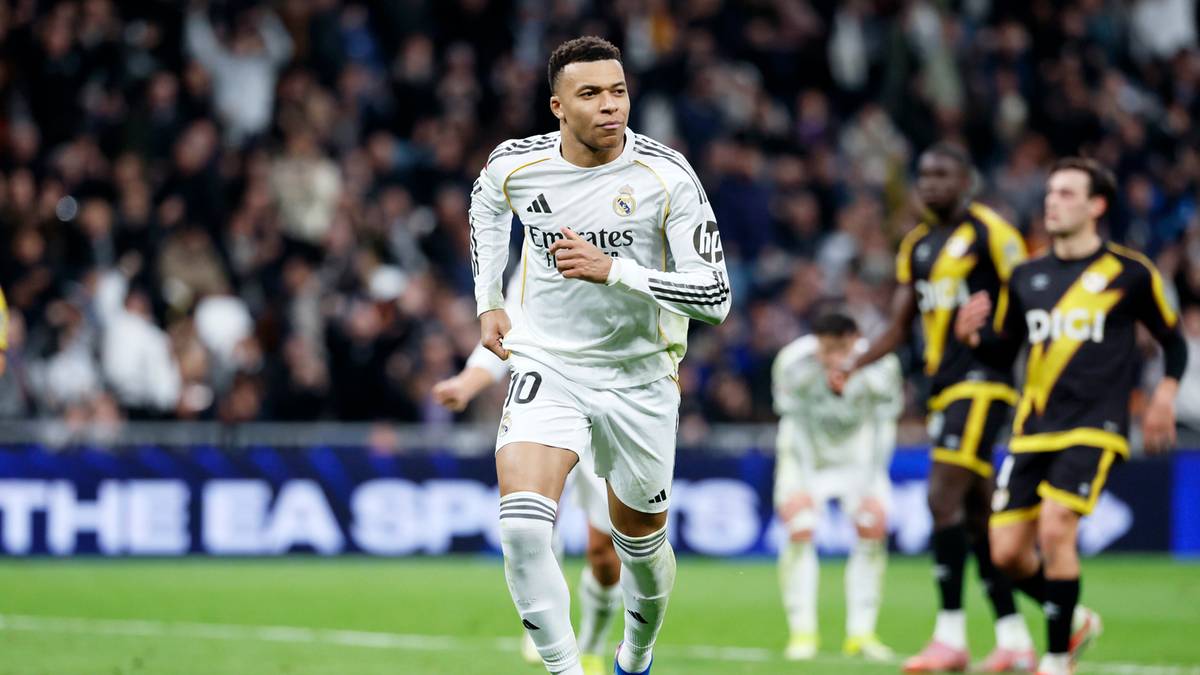 Piłkarz w białej koszulce Realu Madryt biegnie po boisku.