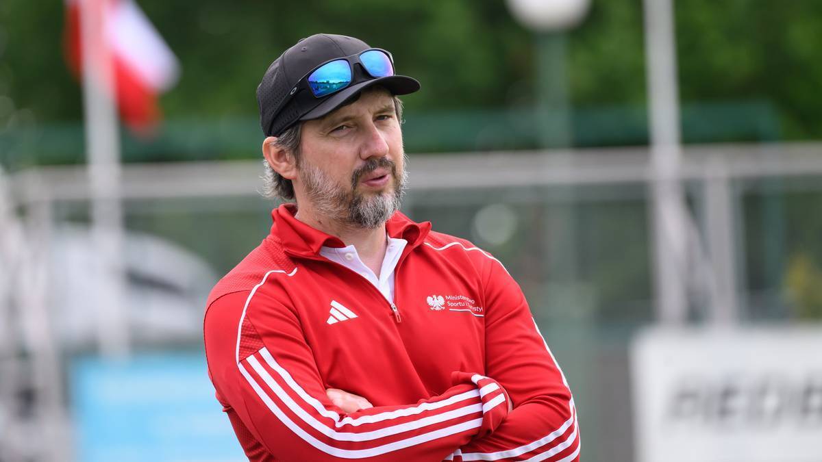 Mężczyzna w stroju sportowym z czapką i okularami przeciwsłonecznymi, w tle flaga Polski.