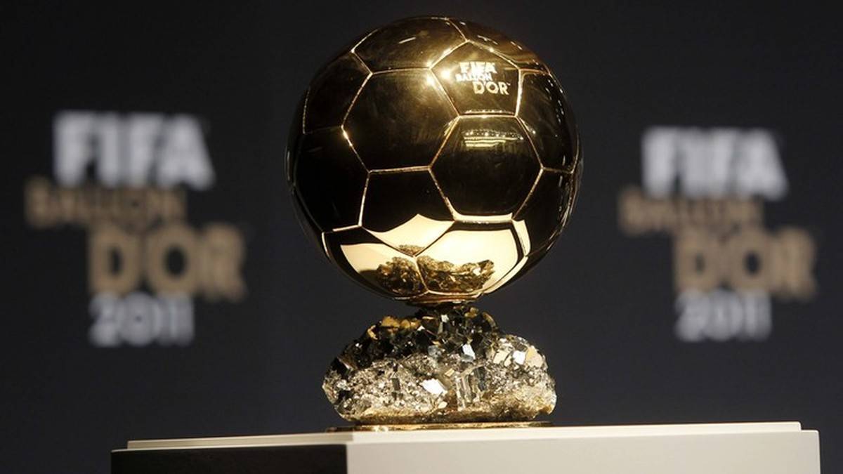 Zbliżenie na Złotą Piłkę FIFA, która jest przedstawiona na okazałym postumencie. W tle widoczne są logotypy FIFA Ballon d'Or.