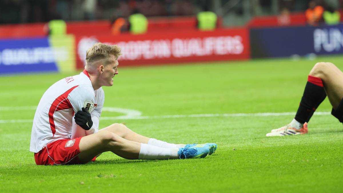 Piłkarz reprezentacji Polski siedzi na murawie stadionu