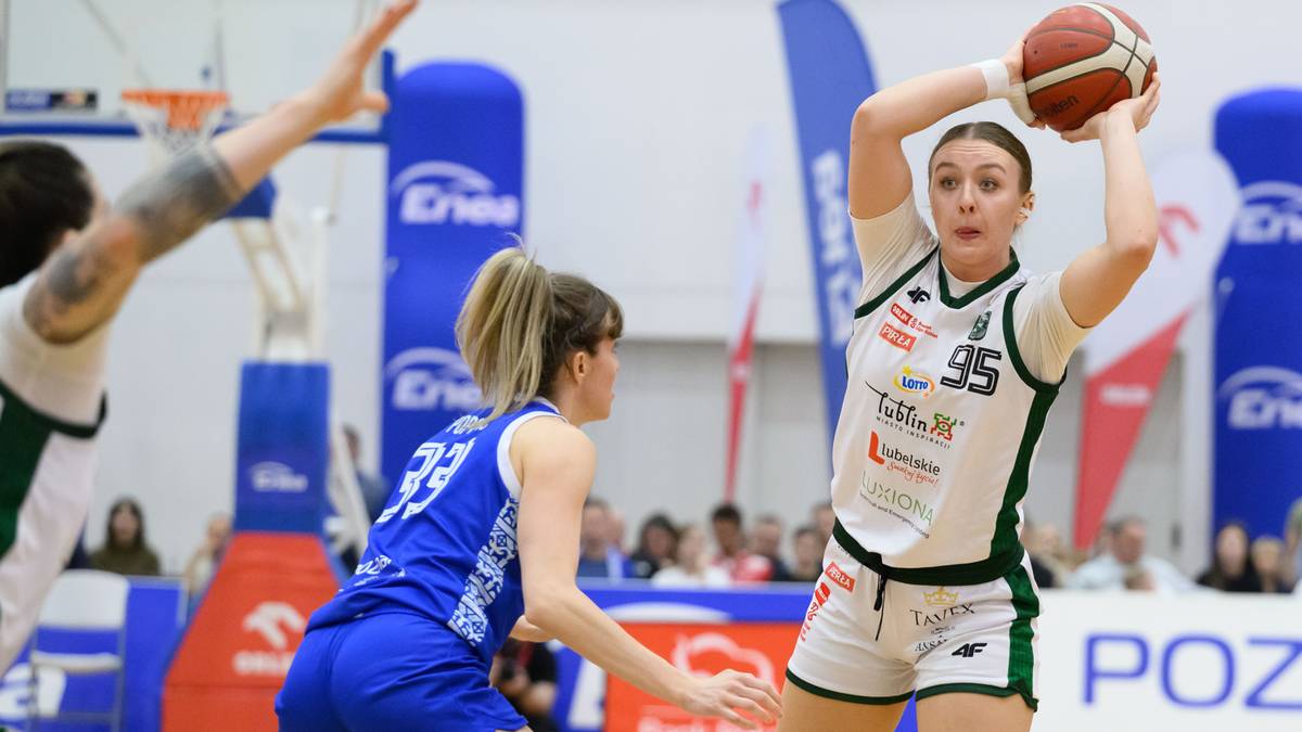 Koszykarka w białym stroju z numerem 95 na plecach rzuca piłkę do kosza. W obronie stoi koszykarka w niebieskim stroju.