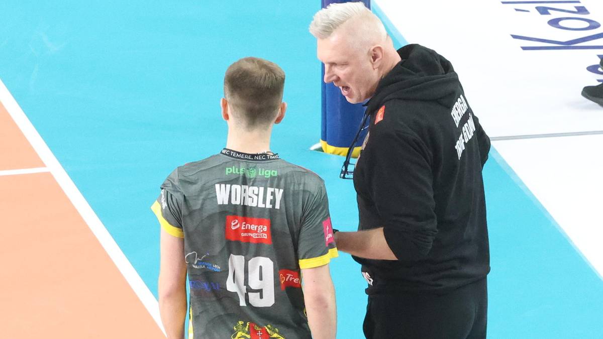 Trener siatkarskiej drużyny rozmawia z zawodnikiem na boisku.