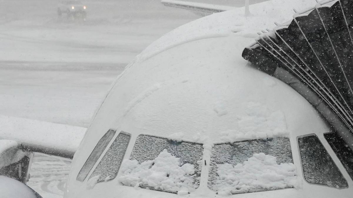Samolot pokryty śniegiem na płycie lotniska.