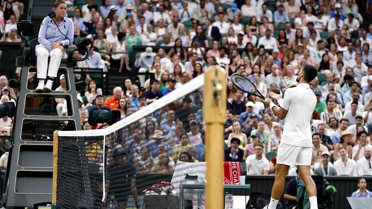 Tenisista podczas meczu na Wimbledonie, widziany zza siatki.