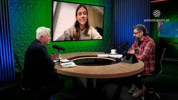 Dwaj mężczyźni w studiu telewizyjnym rozmawiają przy okrągłym stole, podczas gdy na ekranie telewizora nad nimi wyświetlany jest obraz młodej kobiety.