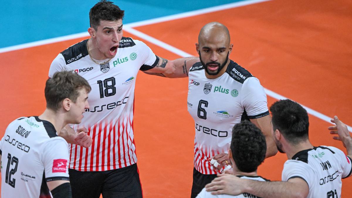 Siatkarze w białych koszulkach drużyny Asseco Resovii gromadzą się na boisku, dyskutując taktykę.