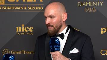 Bartłomiej Dąbrowski w czarnym garniturze z muszką, udziela wywiadu z mikrofonem Polsat Sport.