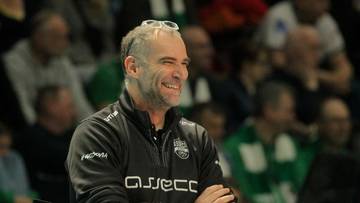 Trener Aluron CMC Warty Zawiercie z okularami na głowie, uśmiecha się z rękami skrzyżowanymi na piersi.