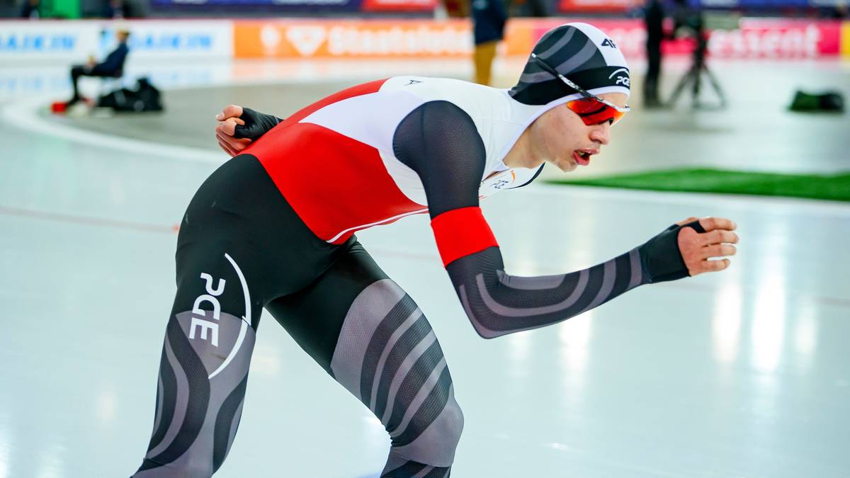 Łyżwiarz szybki w stroju sportowym podczas zawodów na lodowisku.