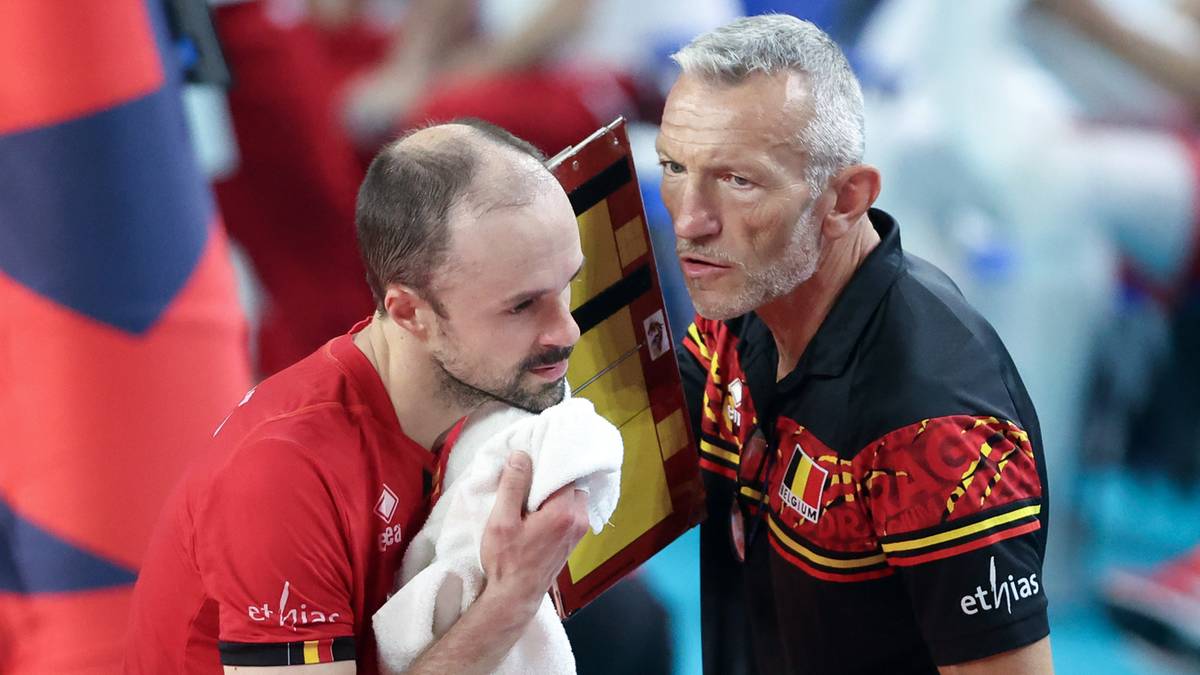 Dw&oacute;ch mężczyzn w strojach sportowych z flagą Belgii rozmawia podczas meczu siatk&oacute;wki.